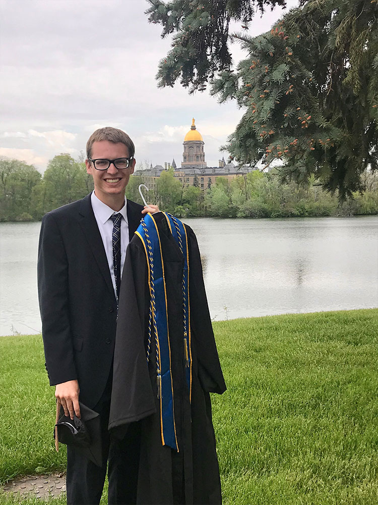 Simon 36 undergrad holding gown across lake golden dome